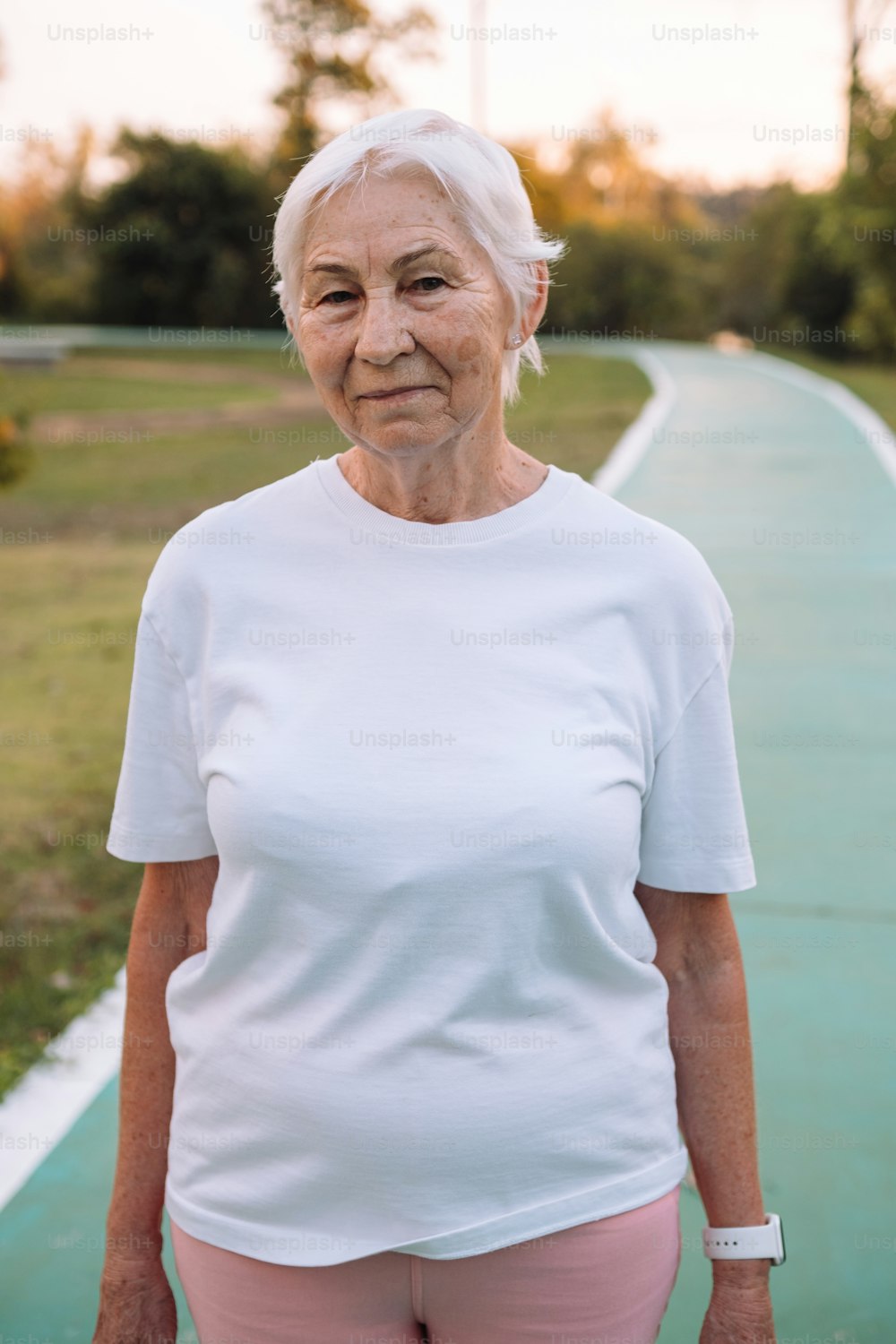 an older woman standing on a path in a park