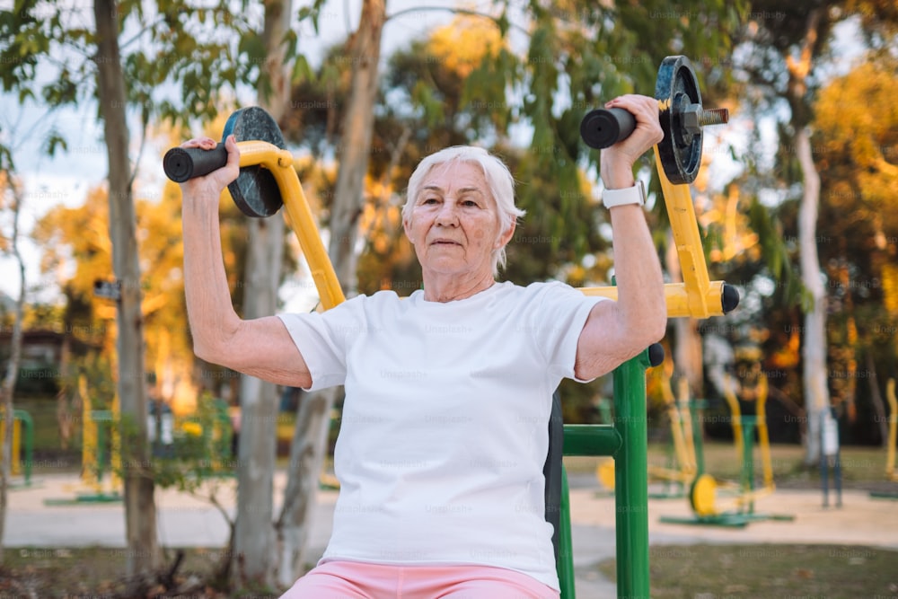 an older woman doing exercises with dumbbells in a park