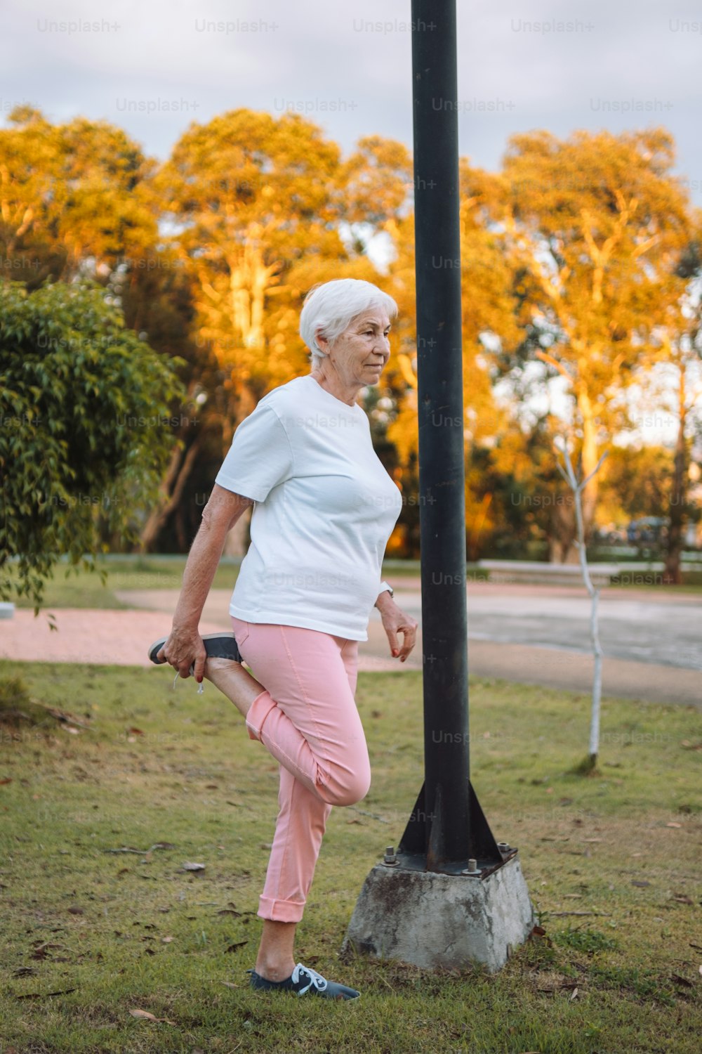 a woman in pink pants standing next to a pole