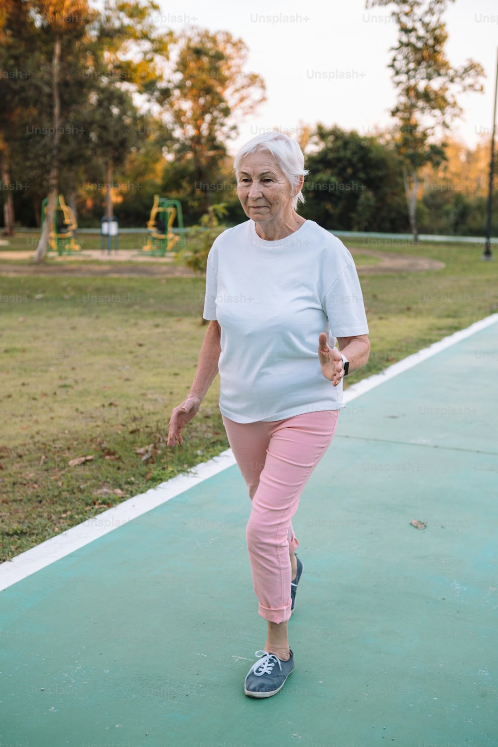 a woman in pink pants and a white t - shirt is walking on a green