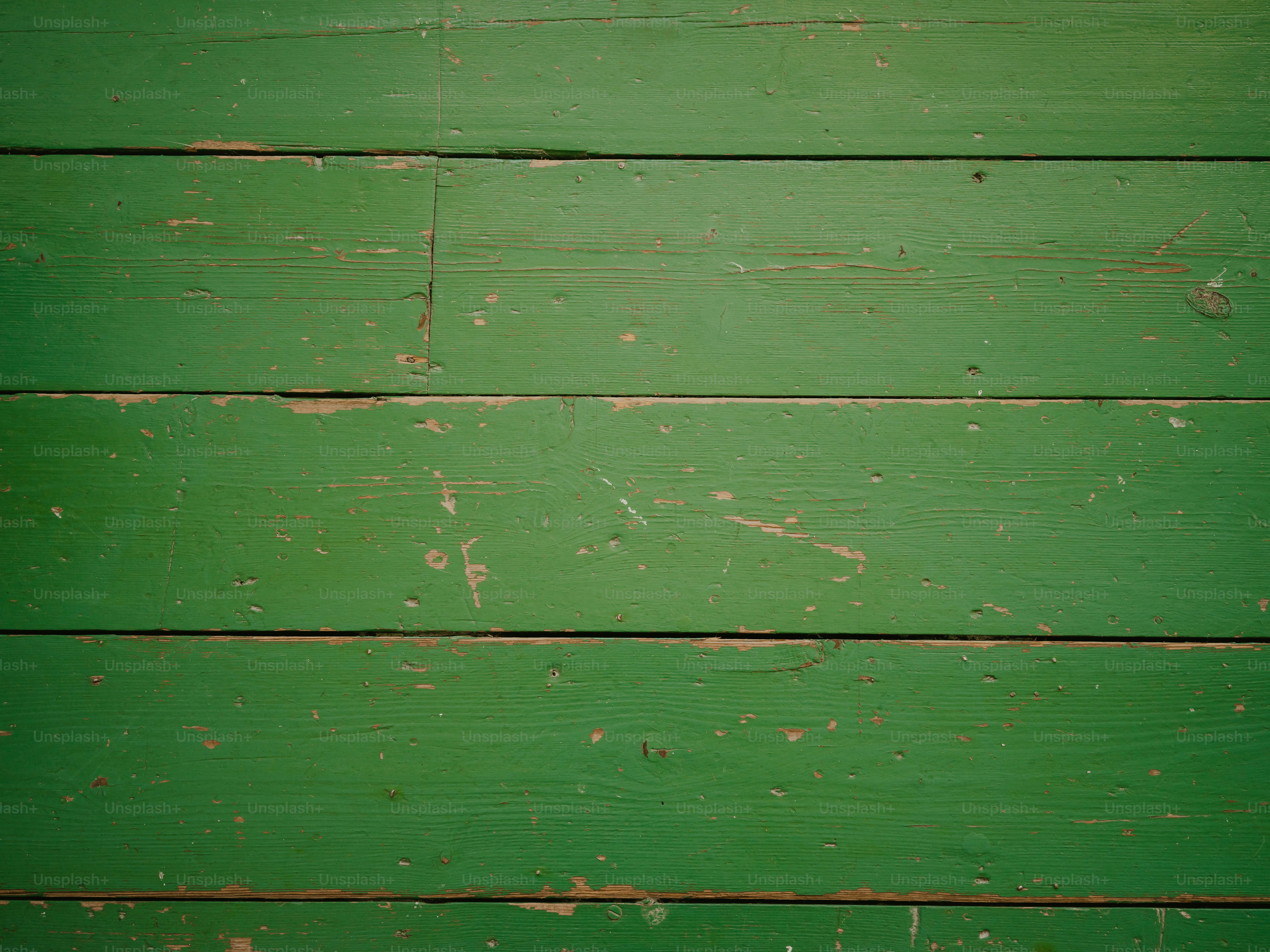 a close up of a green wooden wall with peeling paint