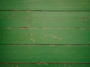 a close up of a green wooden wall with peeling paint