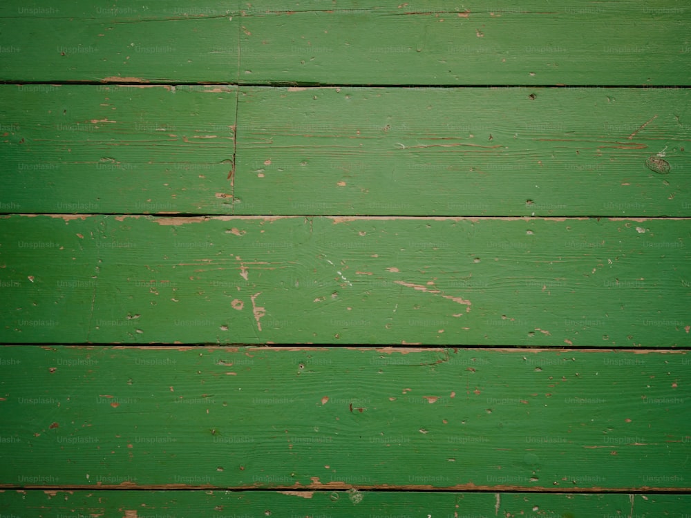a close up of a green wooden wall with peeling paint