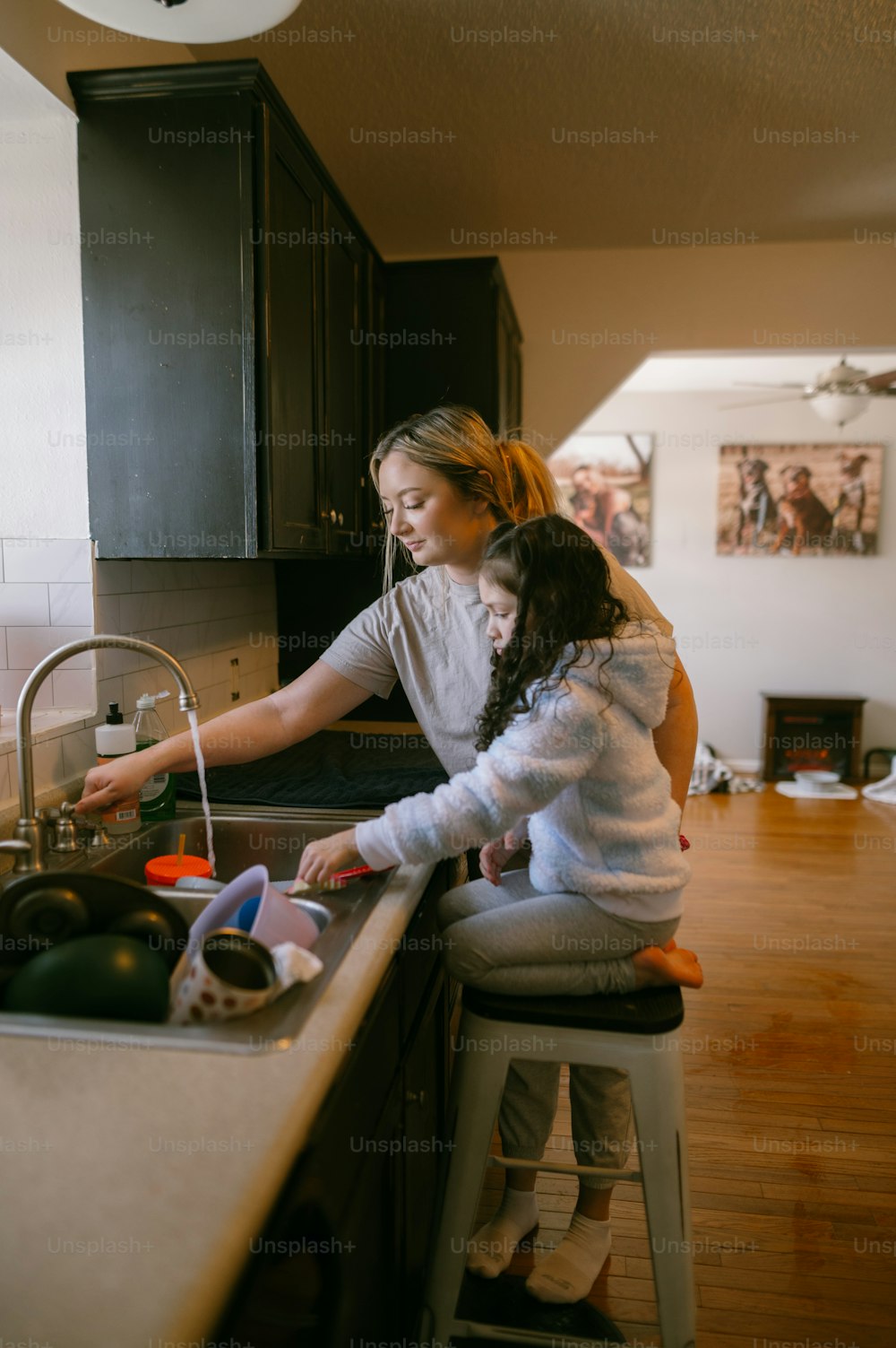 a woman and a child washing dishes in a kitchen