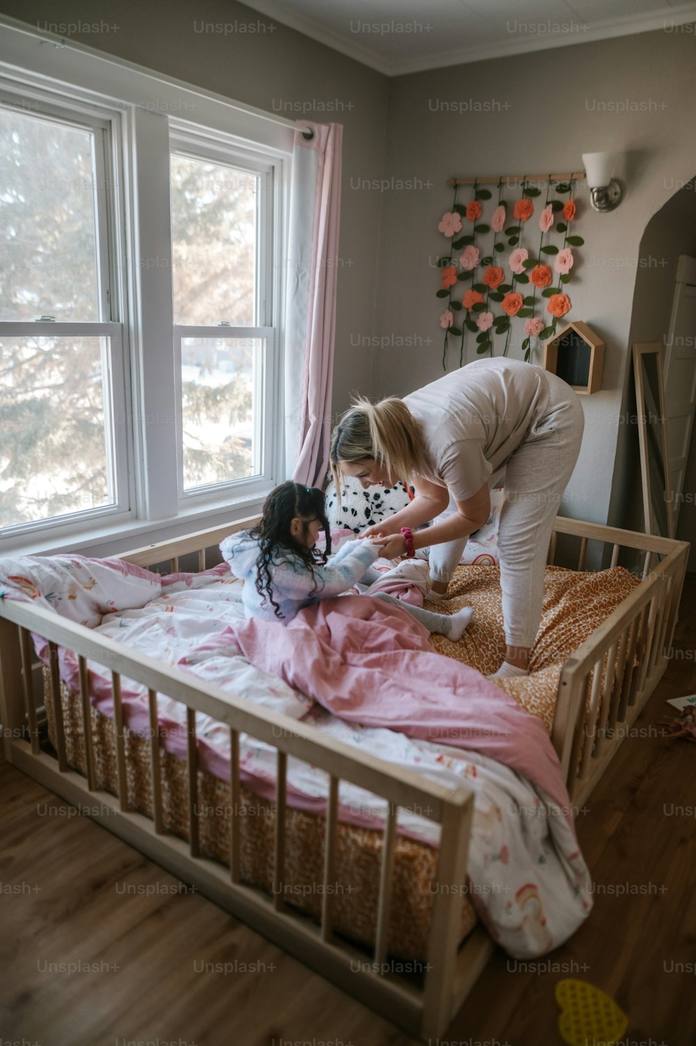 a woman standing over a little girl in a bed