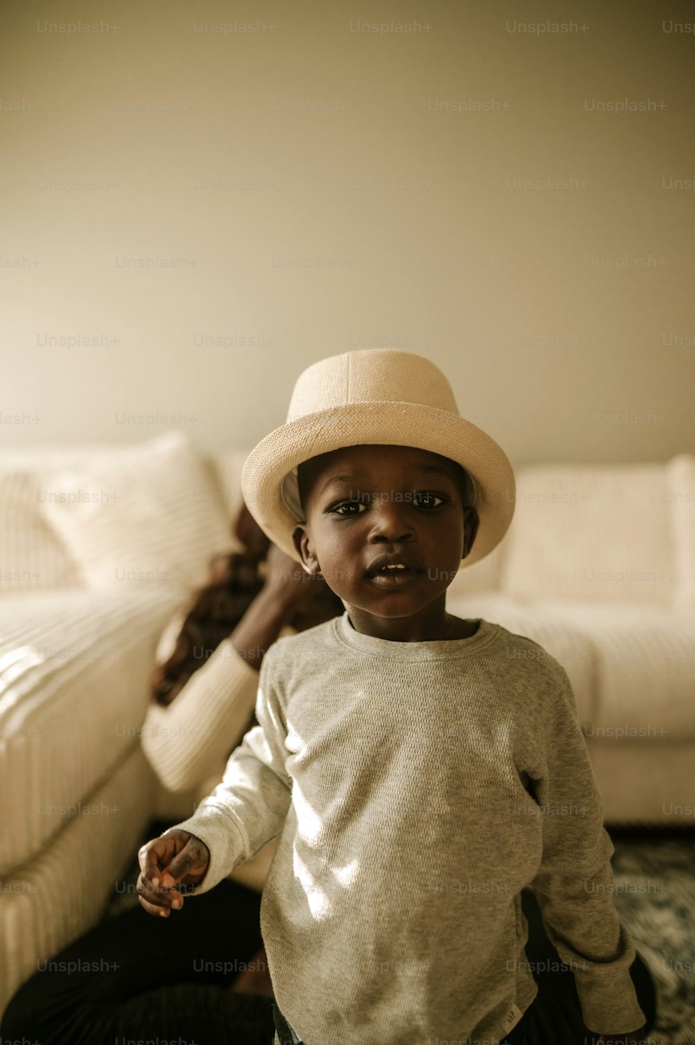 a young boy wearing a hat sitting on the floor
