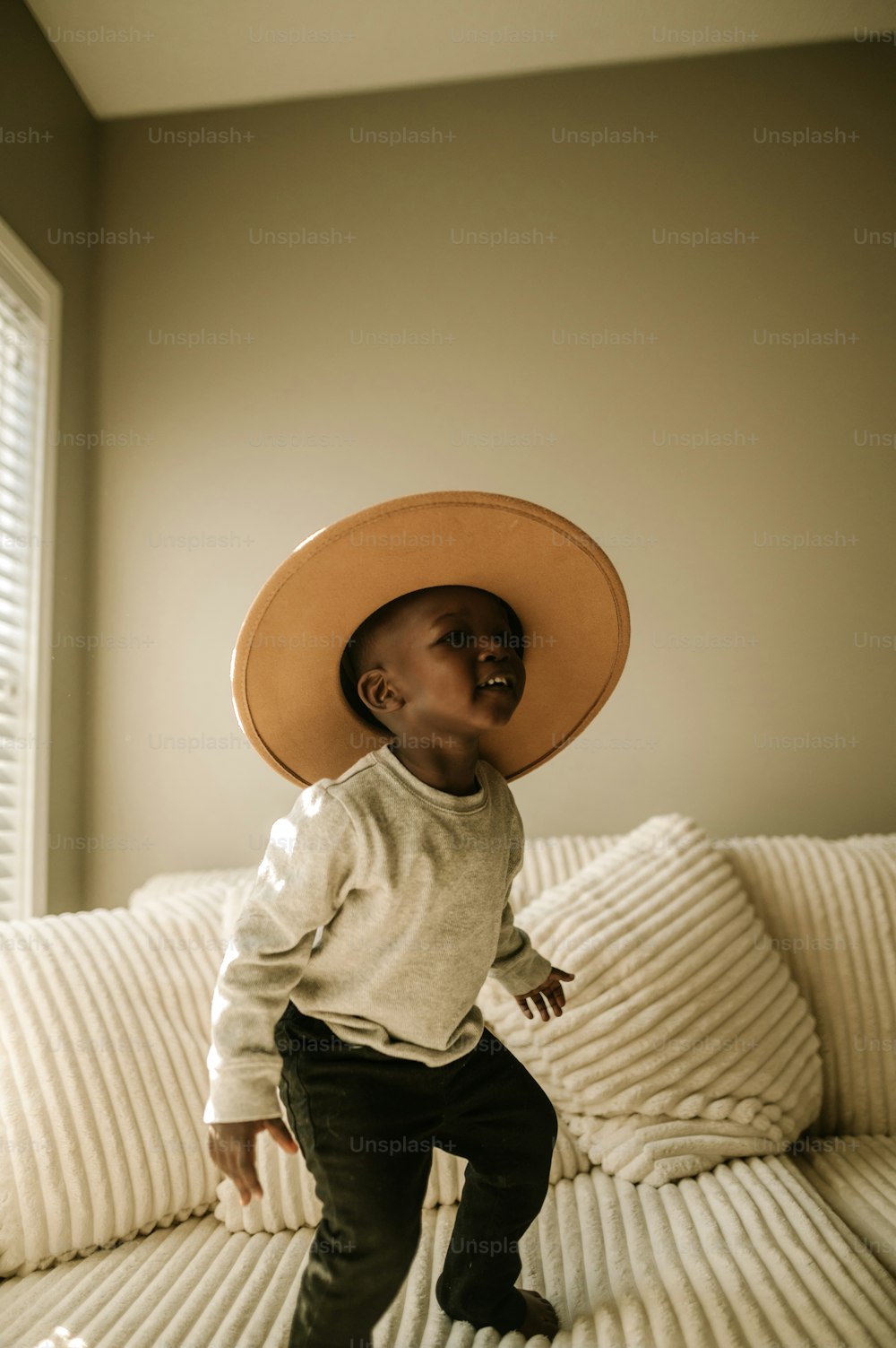 un niño pequeño con un sombrero encima de una cama
