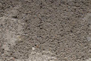 a close up of a cement wall with dirt on it