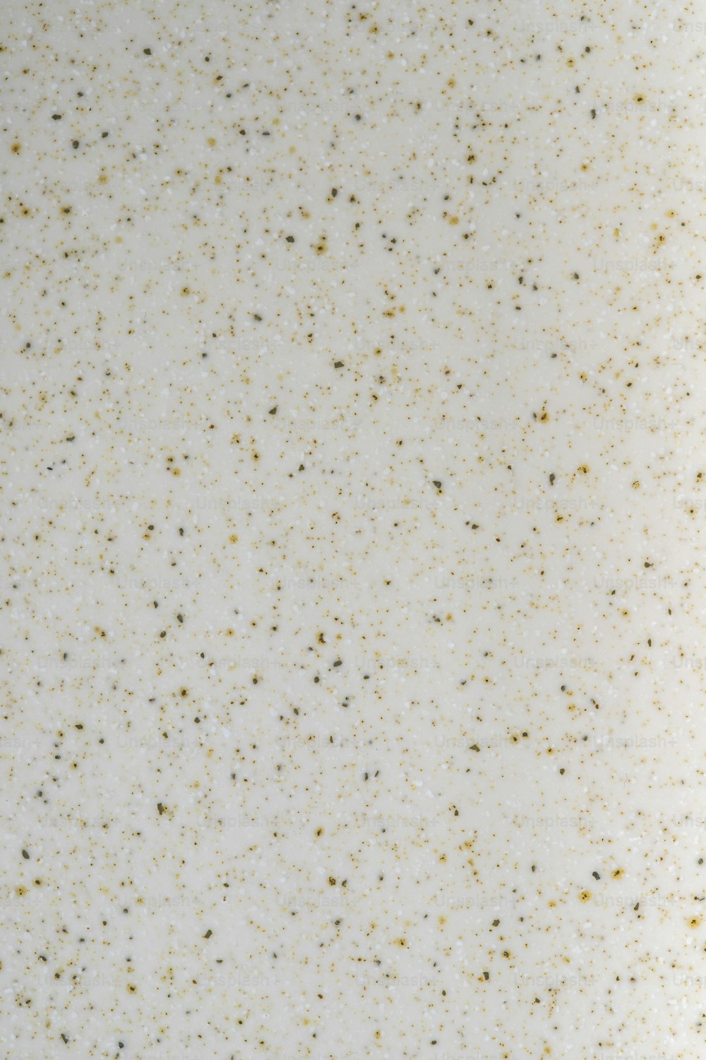 a close up of a white surface with gold speckles