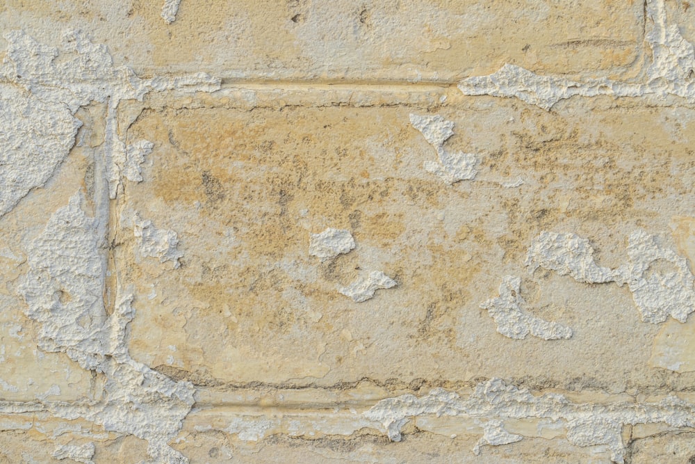 a close up of a stone wall with peeling paint