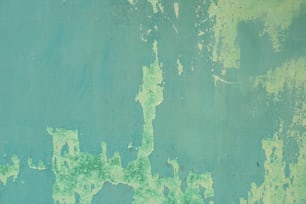 a blue and green wall with peeling paint