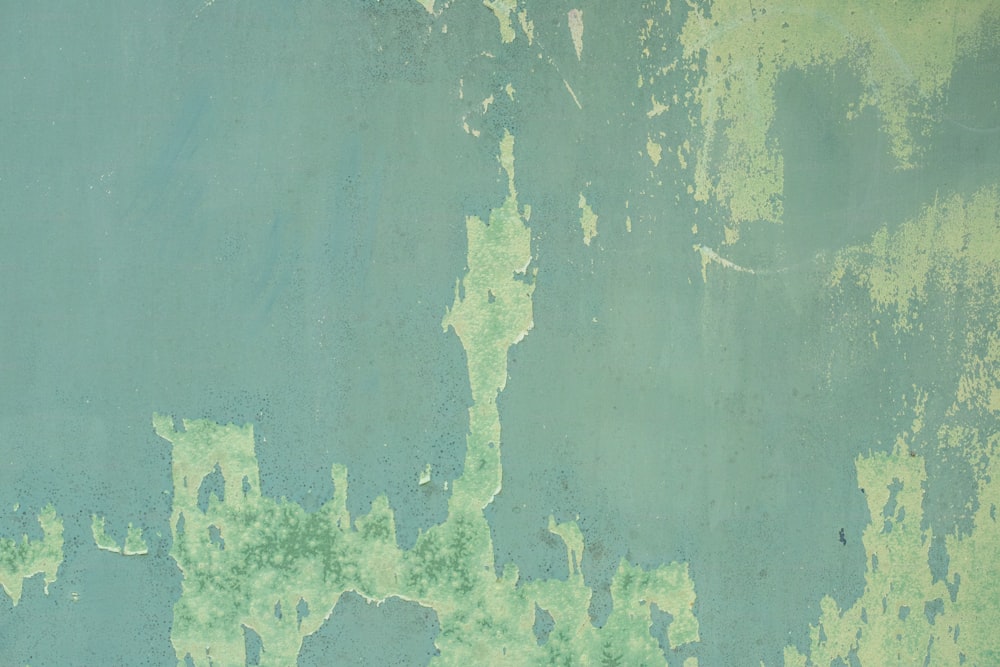 a blue and green wall with peeling paint