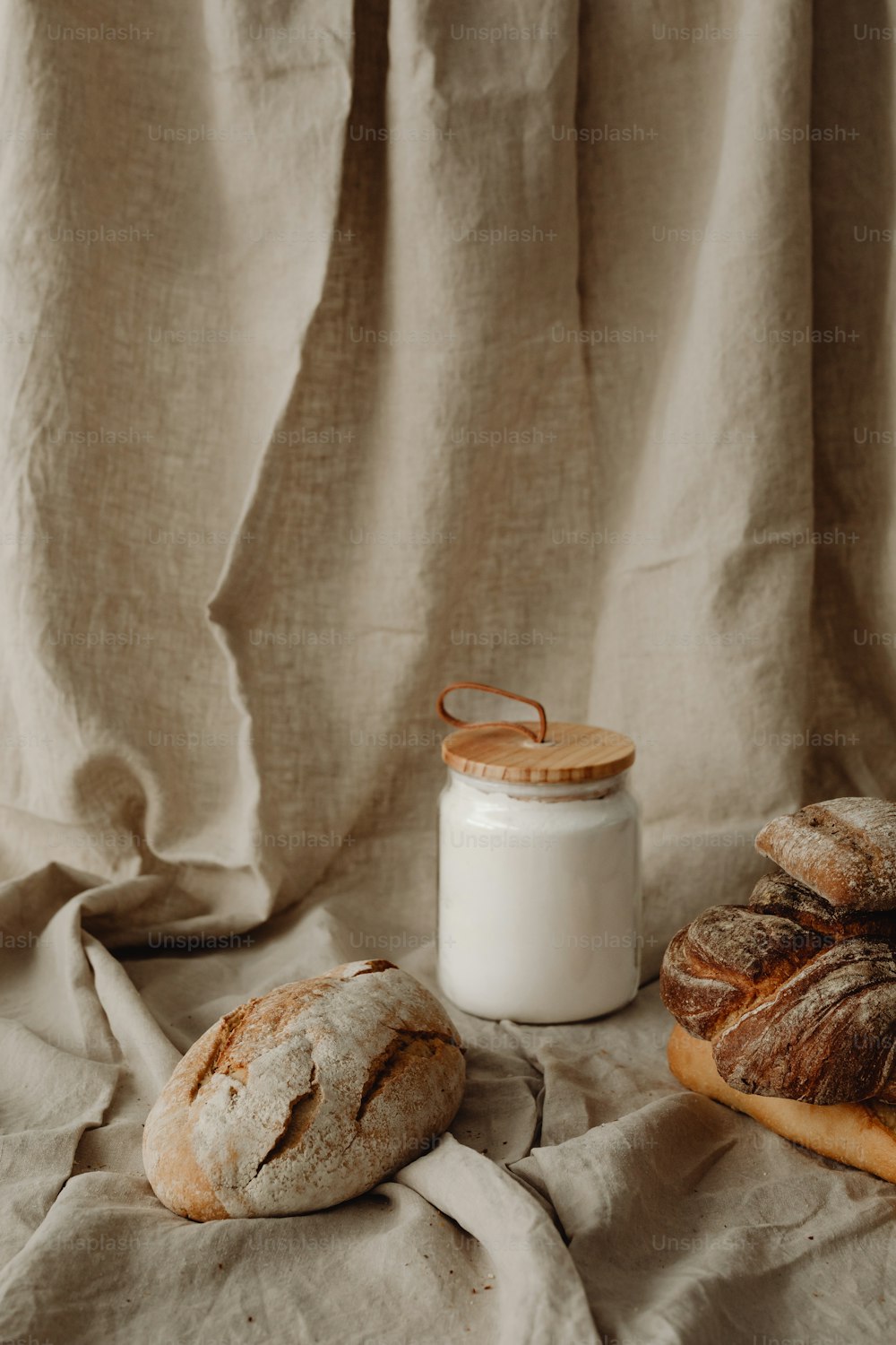 two loaves of bread next to a jar of milk