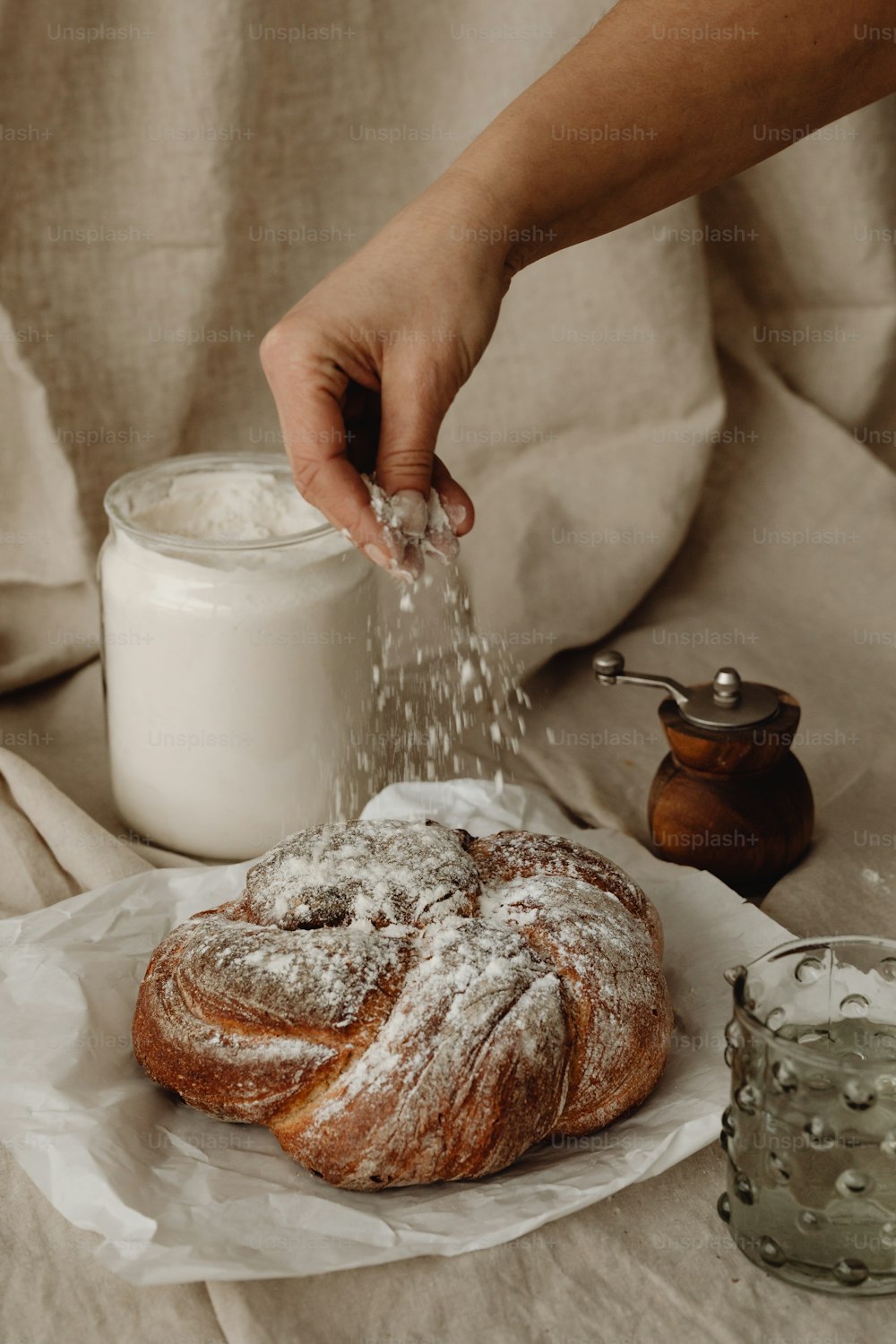 uma pessoa polvilhando açúcar em um bagel