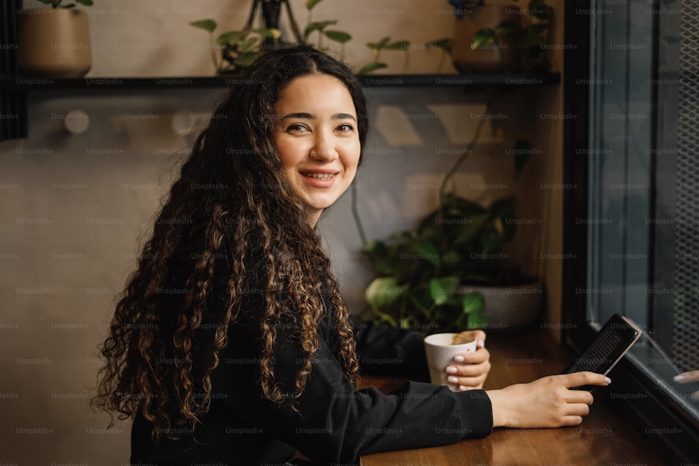 a woman sitting at a table with a cup of coffee