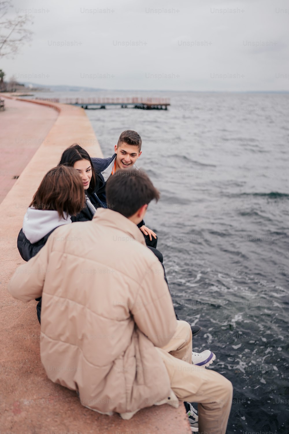 a group of people sitting on the edge of a body of water