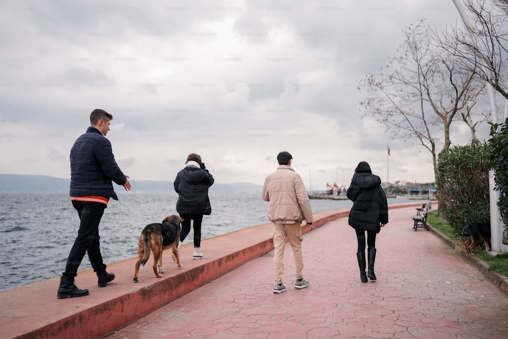 Eine Gruppe von Menschen, die einen Bürgersteig neben dem Meer entlang gehen