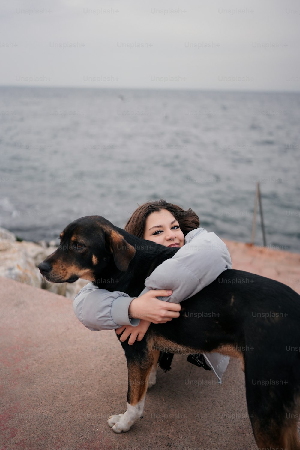a woman hugging a dog on the beach