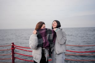 a couple of women standing next to each other near the ocean