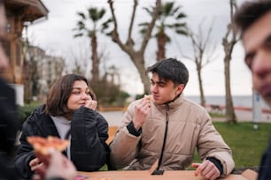 a man and woman sitting at a table eating pizza