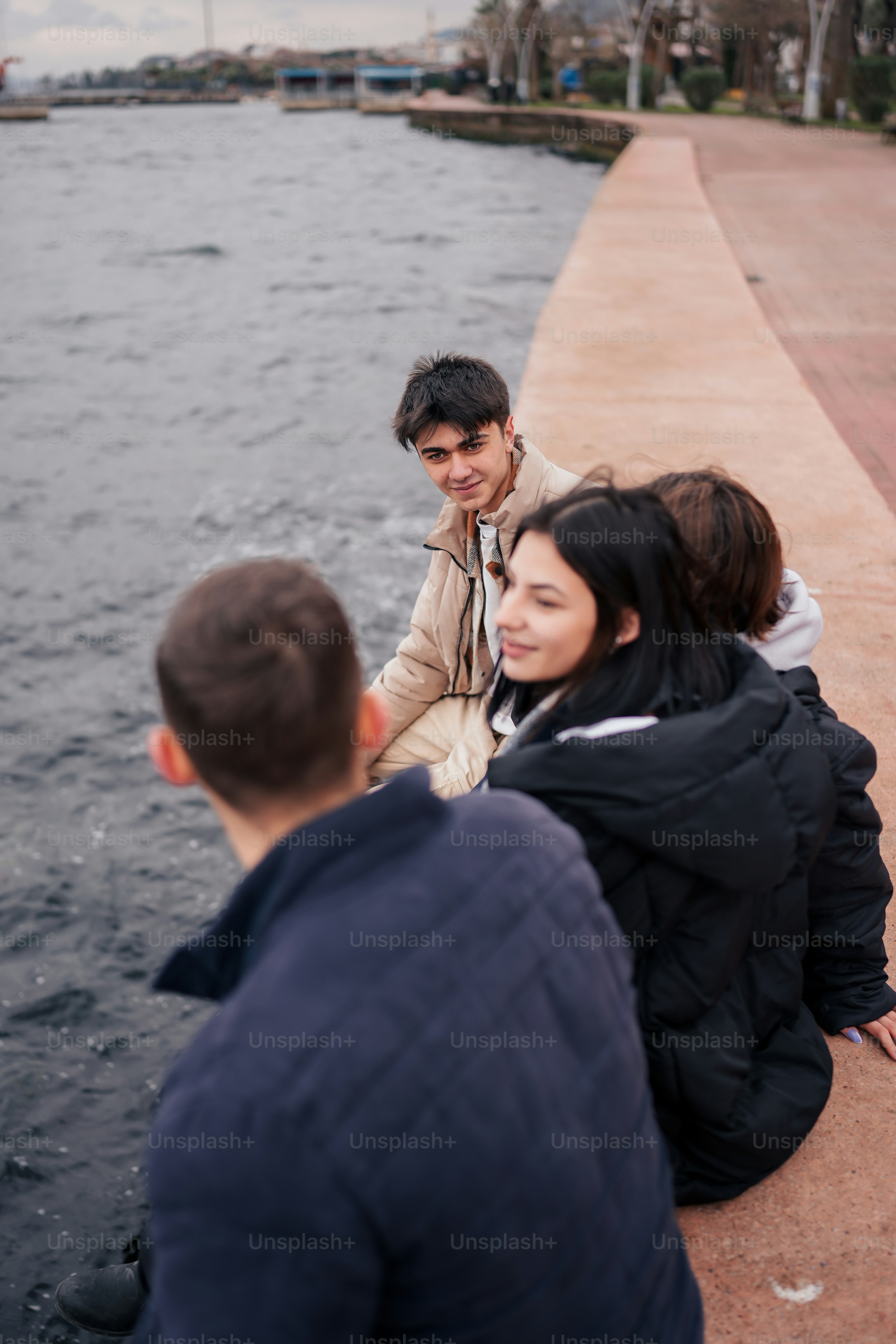 A group of people sitting next to a body of water photo – Travel Image ...