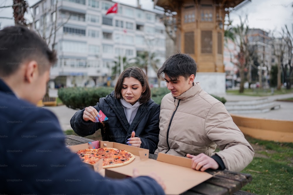 a man and a woman sitting at a table with a box of pizza