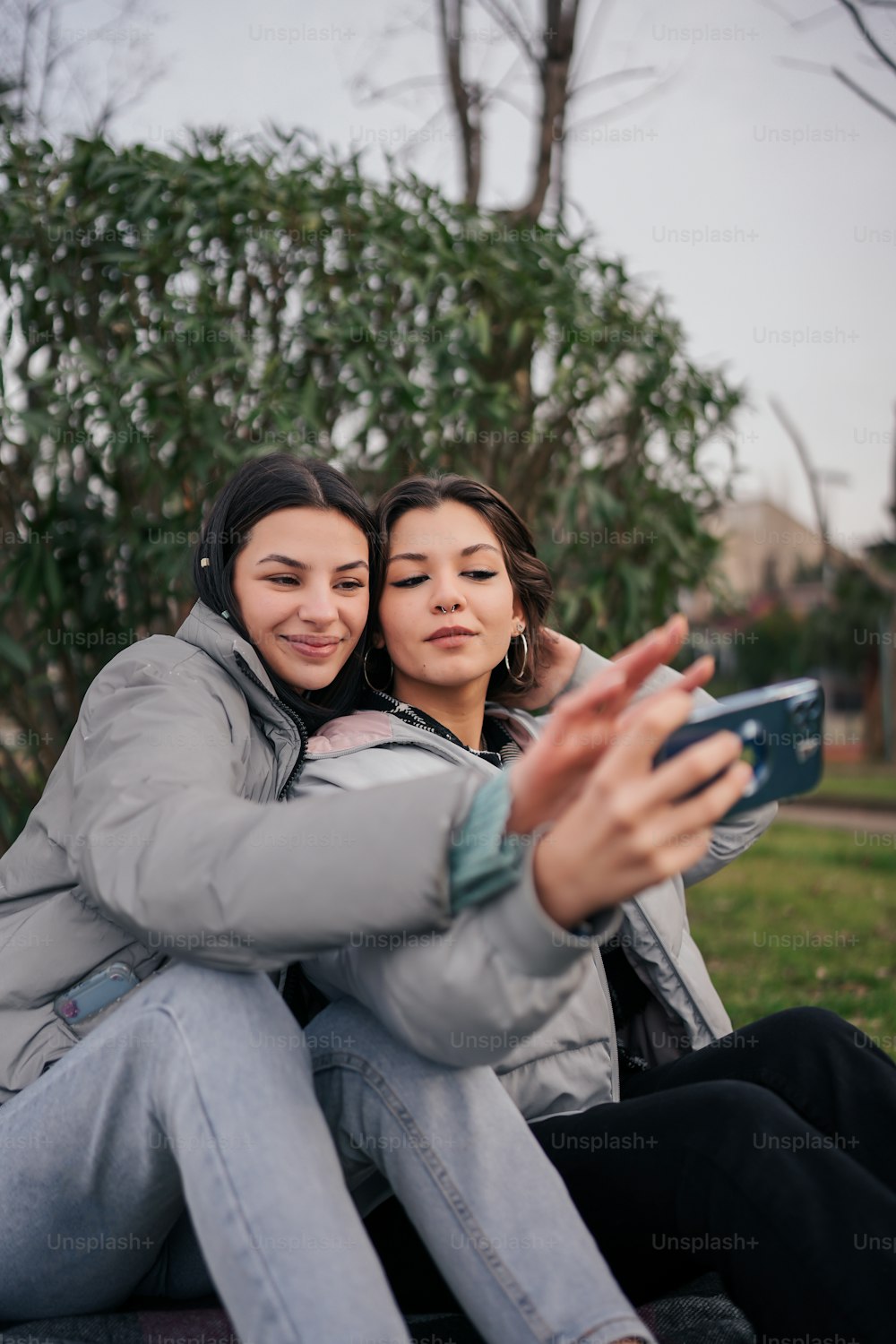 two women sitting on a bench taking a selfie