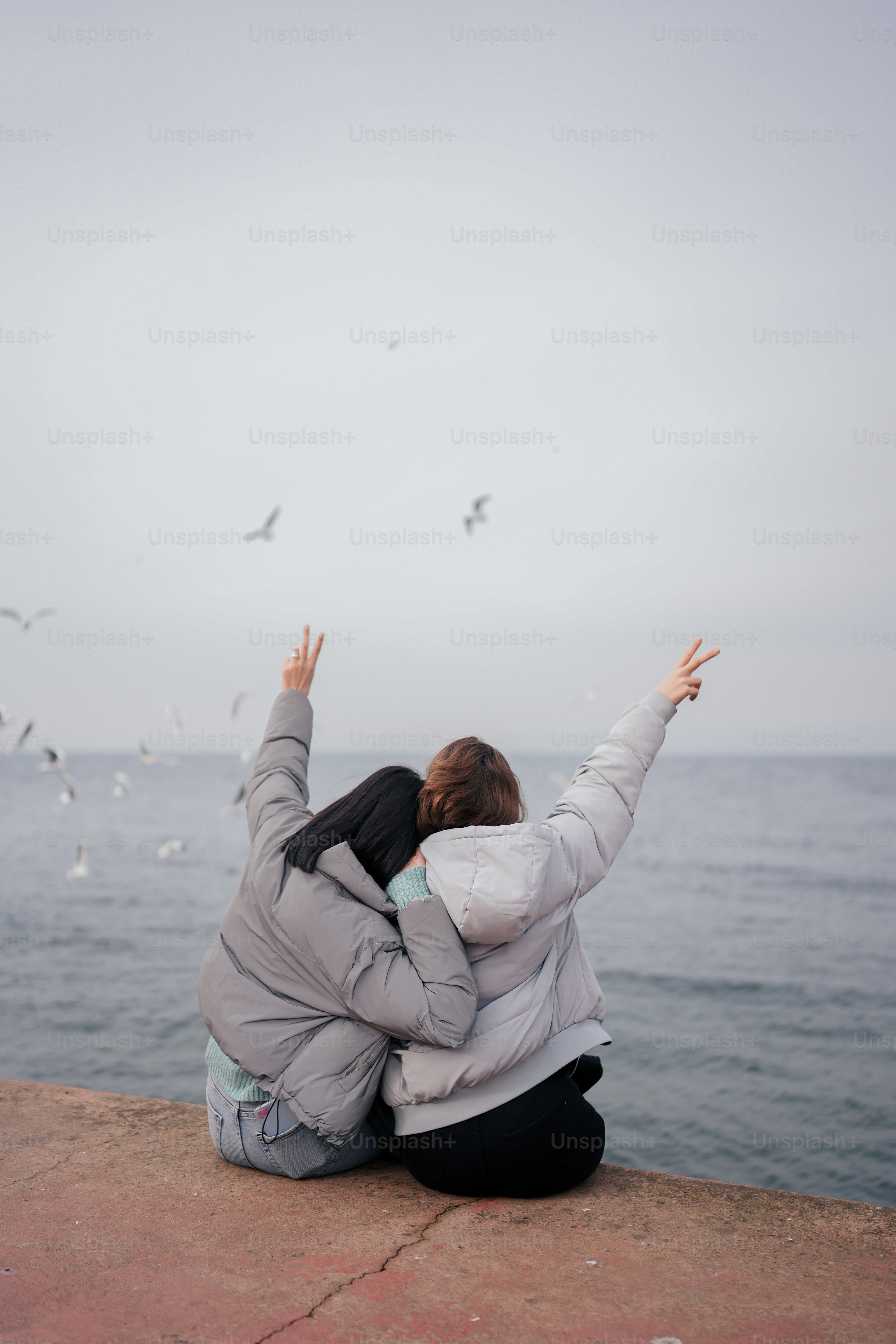 A woman sitting on the edge of a cliff by the ocean photo – Sea Image ...