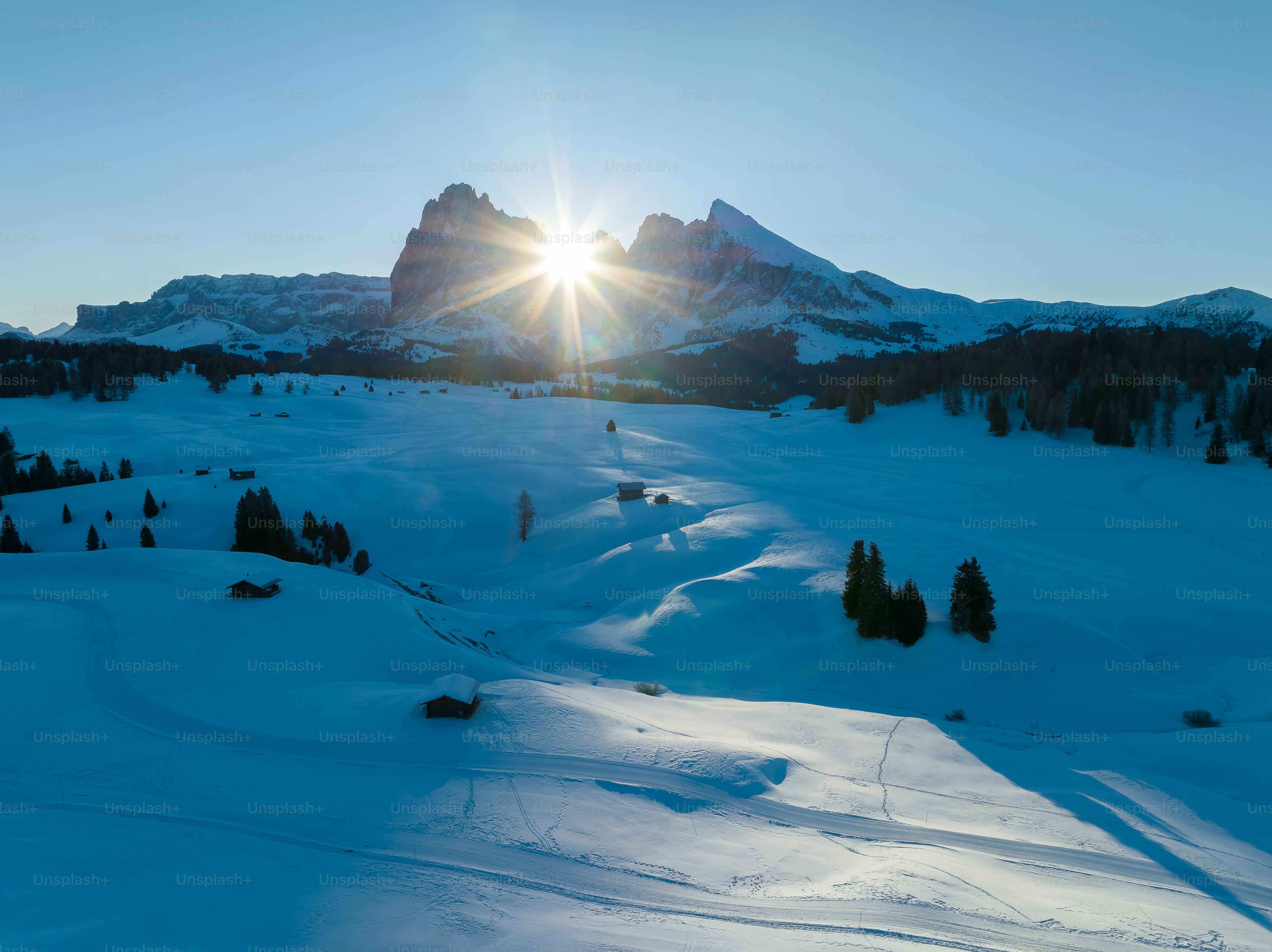the sun is shining over a snowy mountain