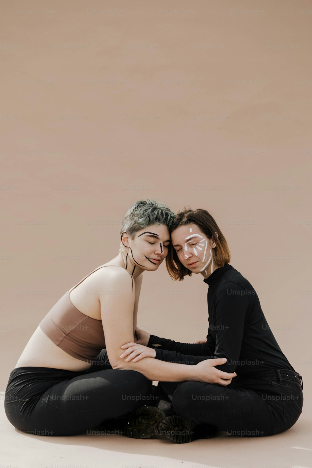 two women sitting on the ground with their arms around each other