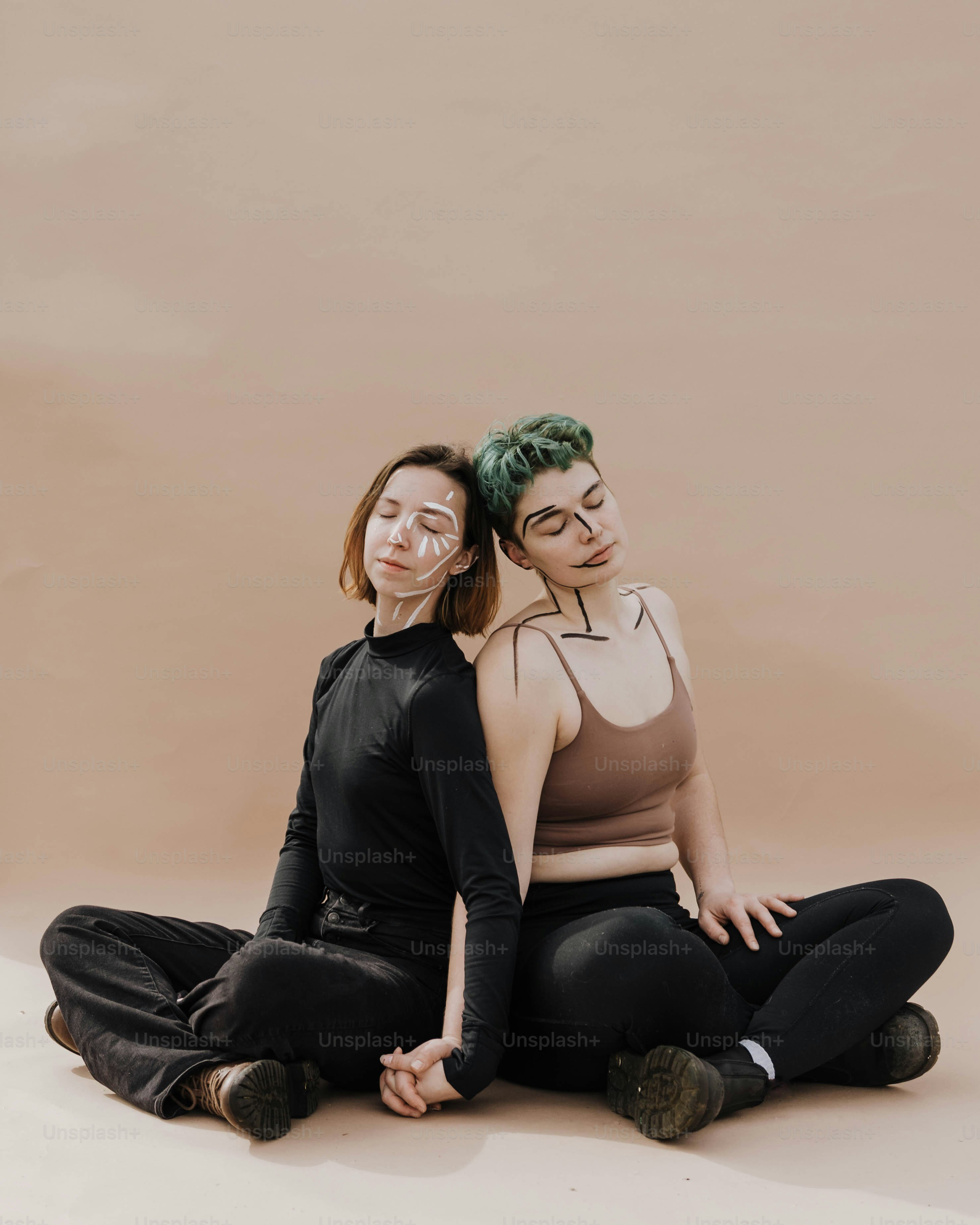 two women sitting on the ground with their arms around each other
