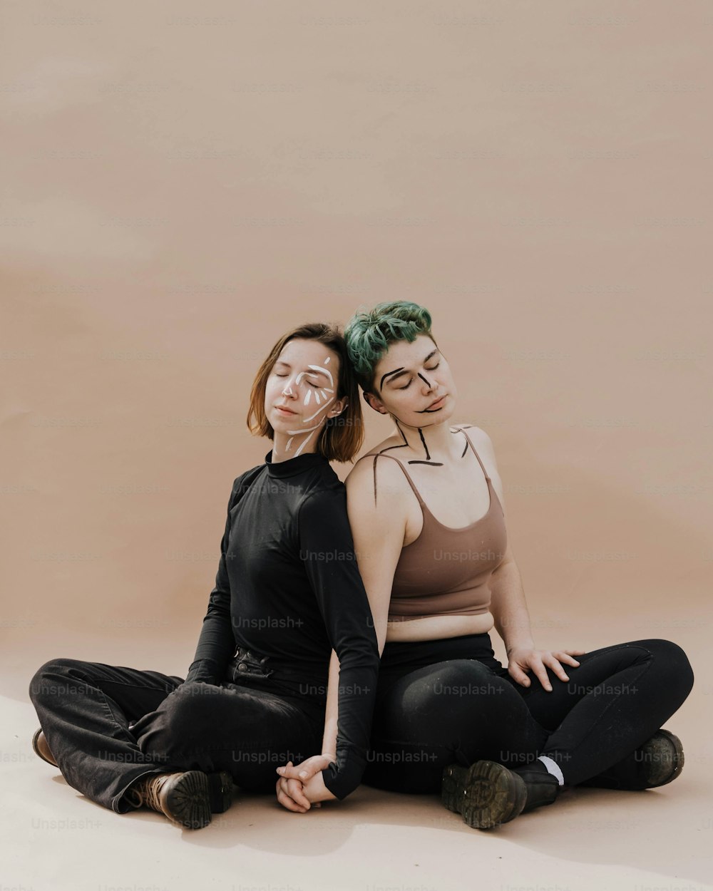 duas mulheres sentadas no chão com os braços em volta uma da outra