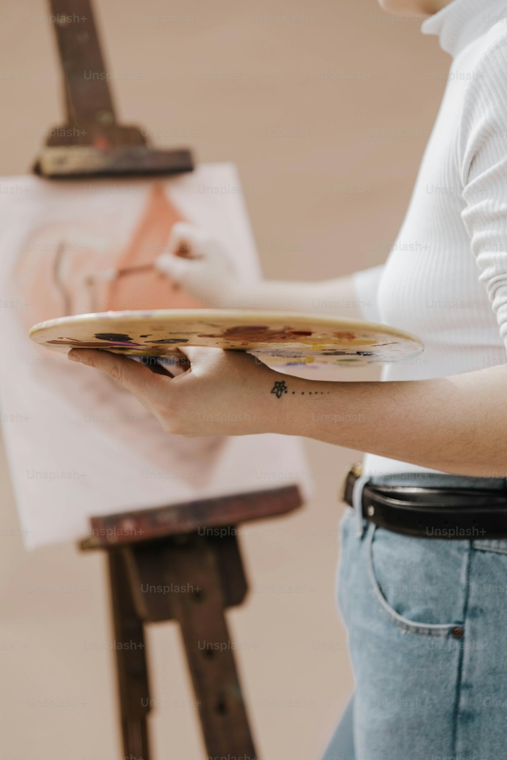 Eine Frau hält einen Pinsel und ein Gemälde auf einer Staffelei
