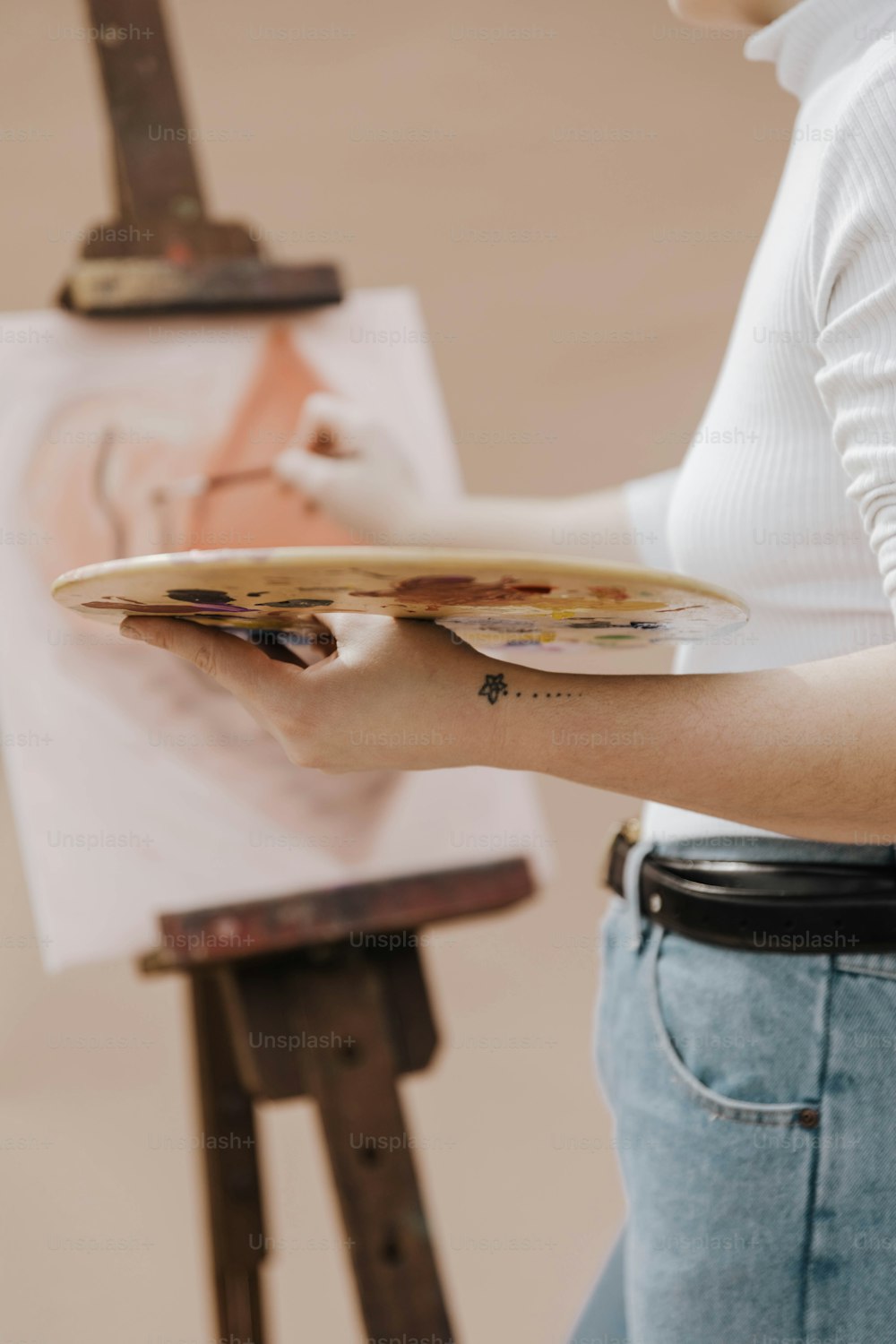 a woman holding a paintbrush and a painting on a easel