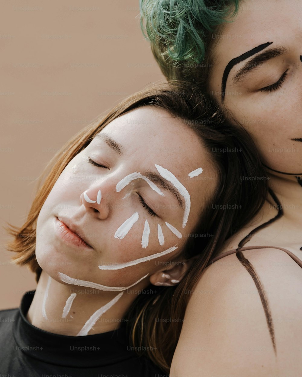 Une femme aux cheveux verts étreignant une femme avec de la peinture blanche pour le visage