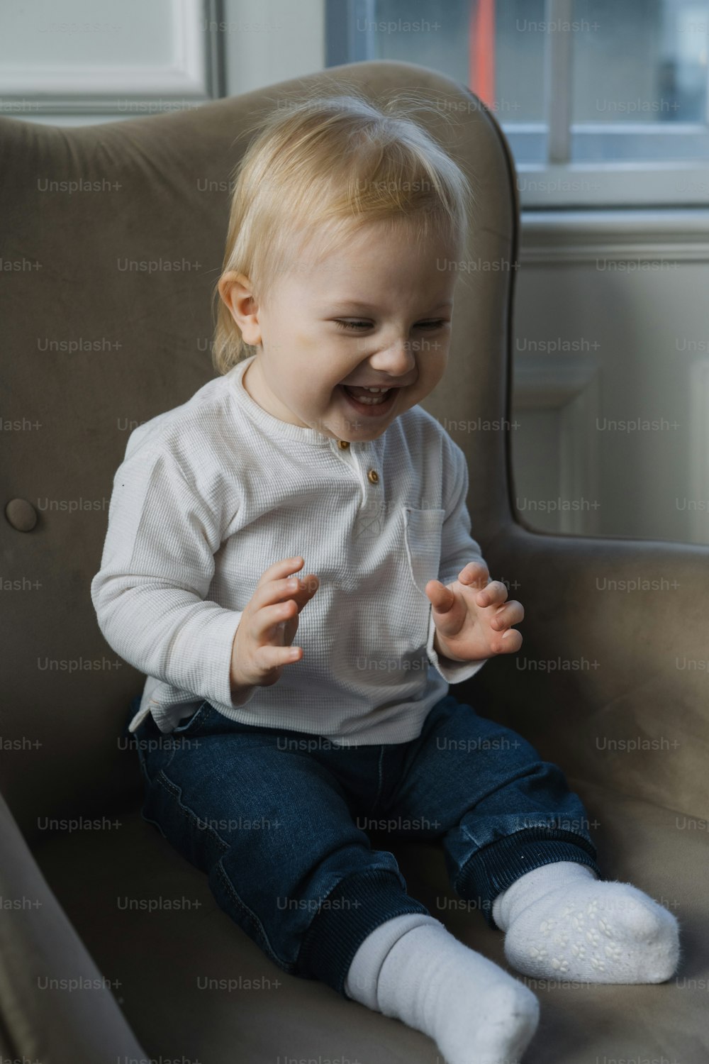 a toddler sitting in a chair laughing