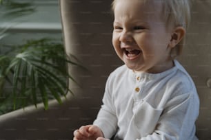 a baby laughing while sitting in a chair