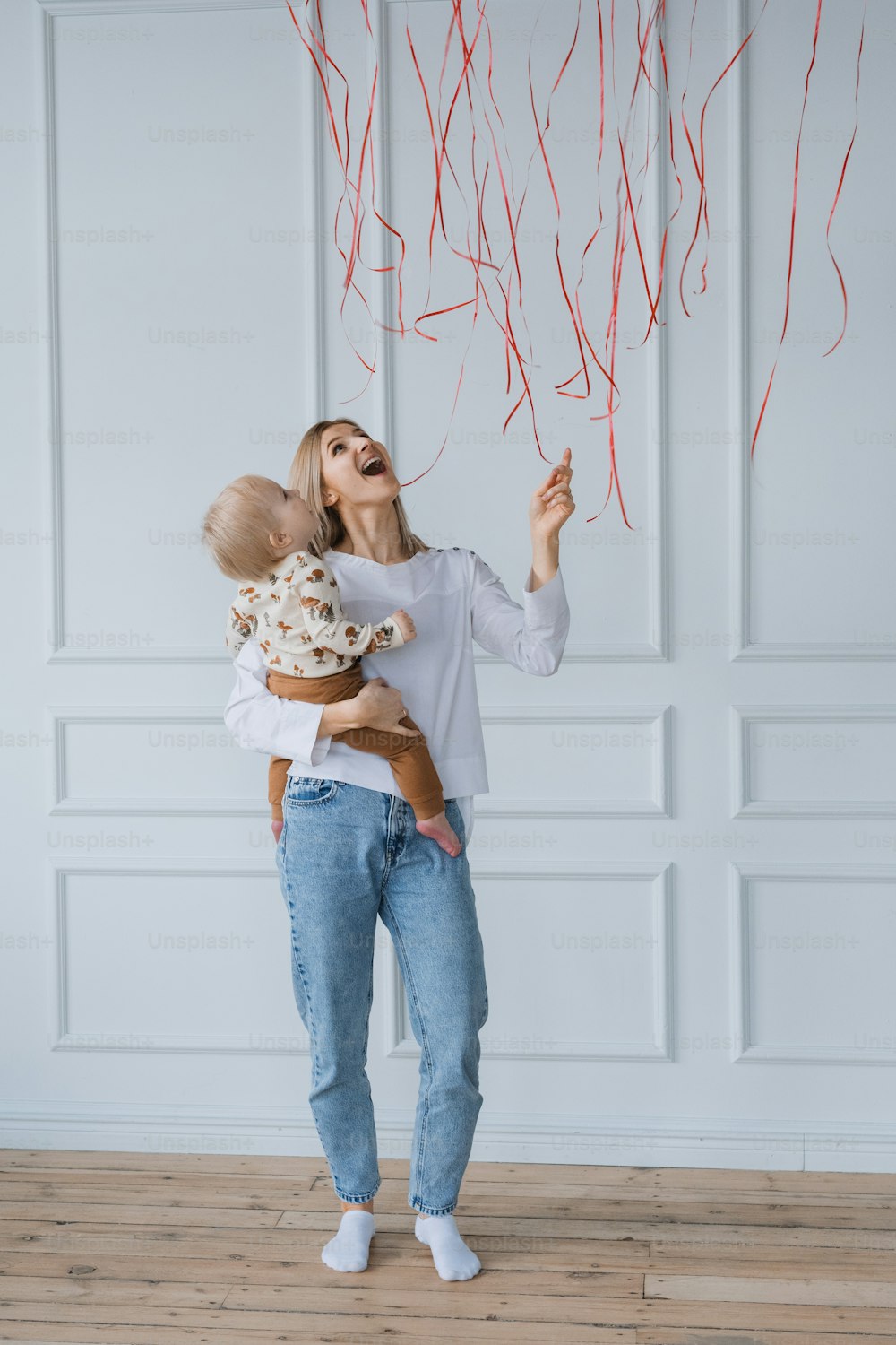 a woman holding a baby while flying red streamers