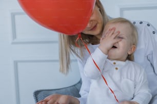a woman holding a red balloon with a small child
