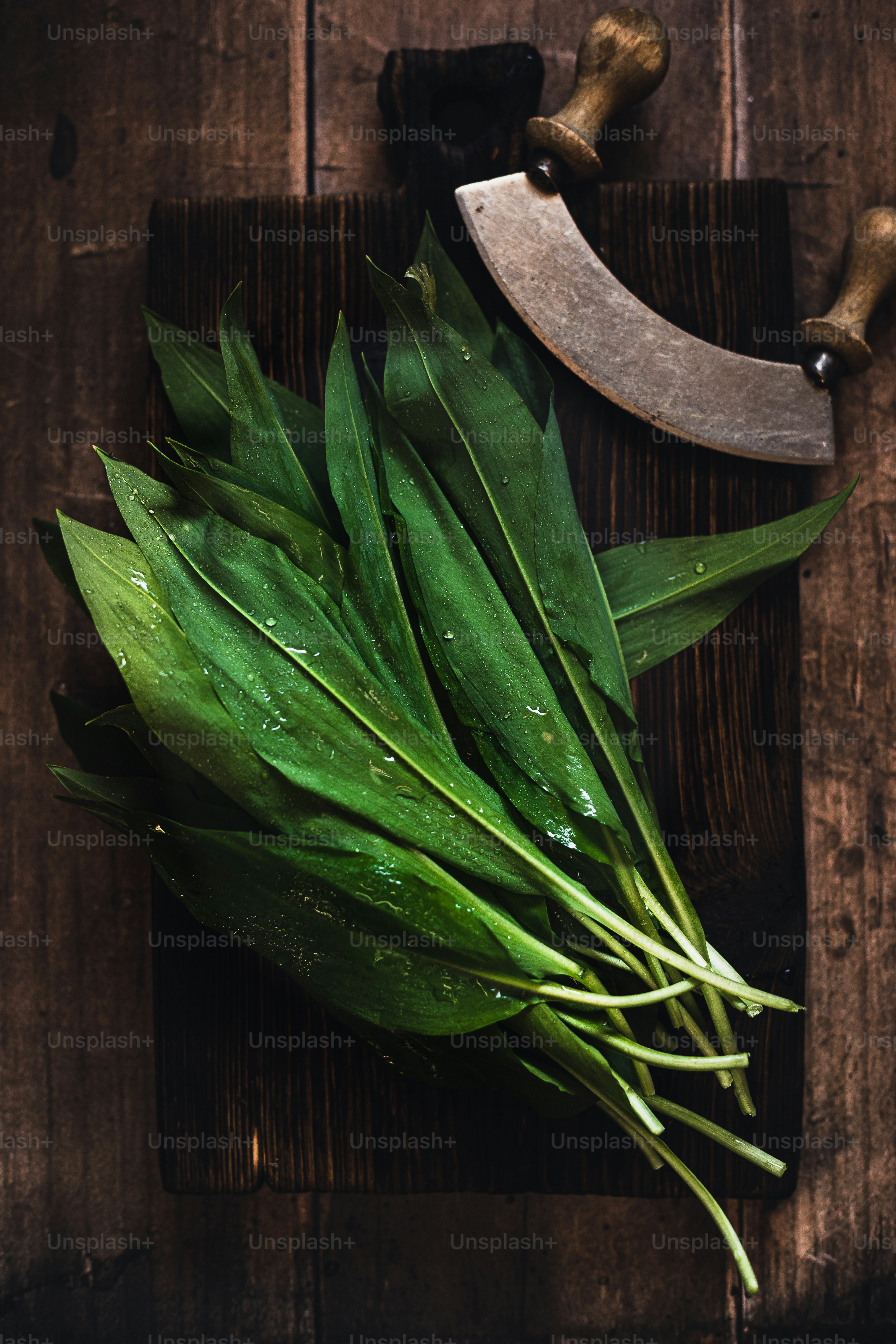 a knife and some green leaves on a cutting board