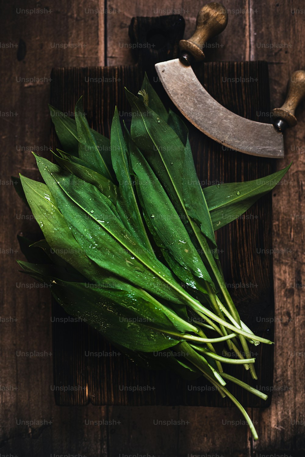 un cuchillo y unas hojas verdes en una tabla de cortar