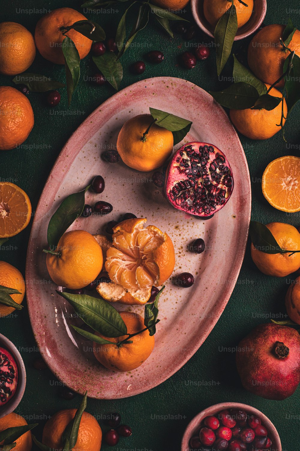 Un plato de naranjas y granadas sobre una mesa
