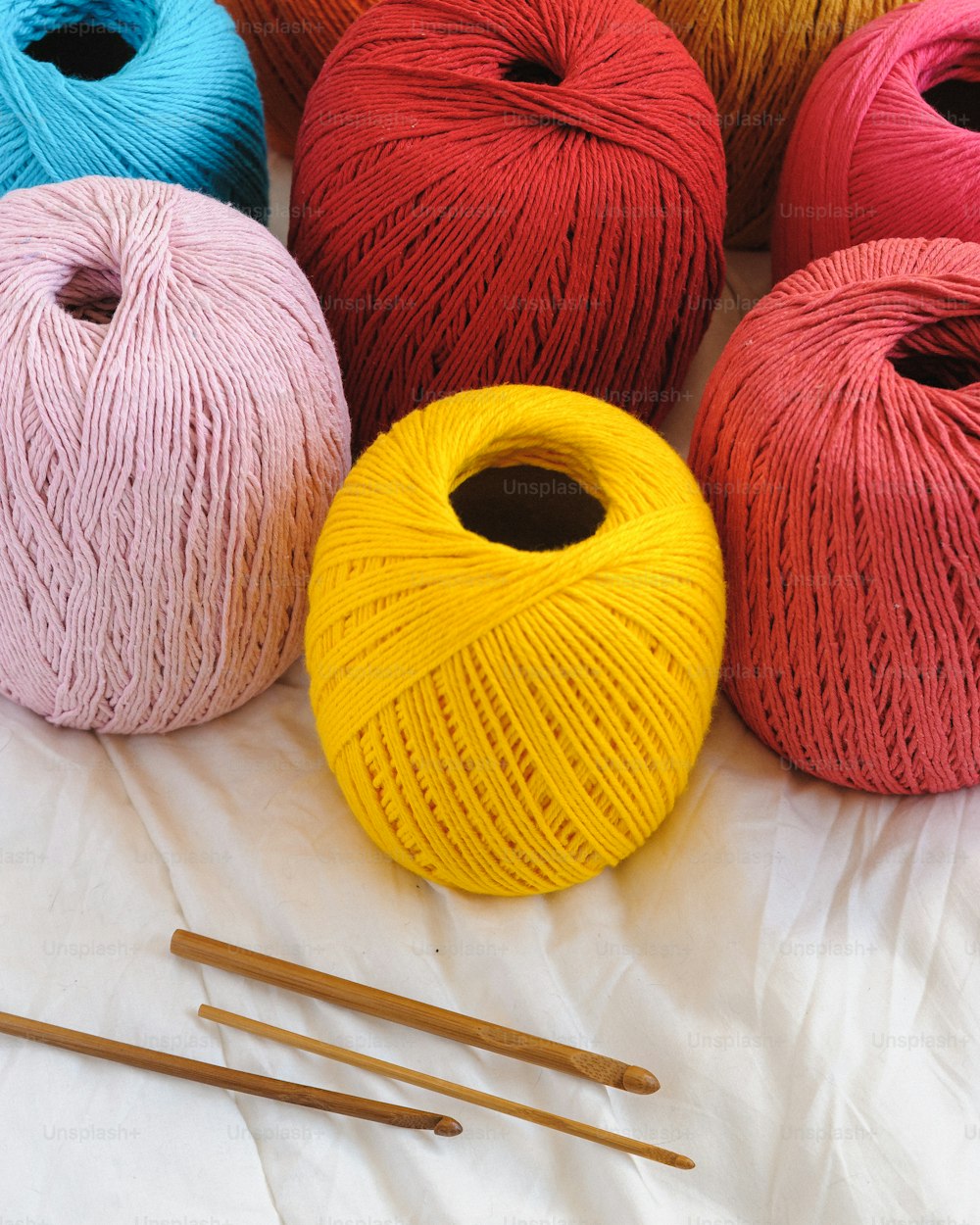 un groupe de pelotes de fil à côté d’aiguilles à tricoter