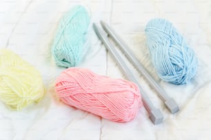three skeins of yarn and a crochet hook on a bed