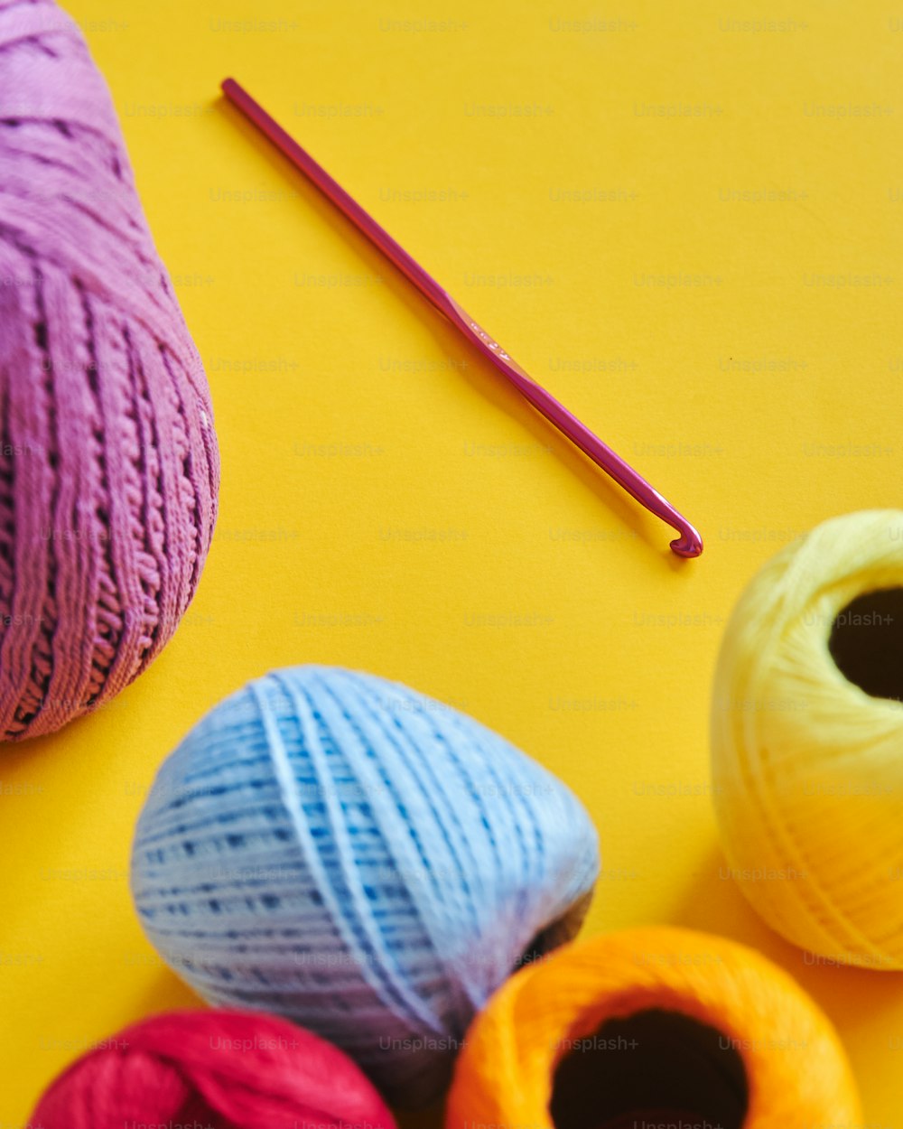 a group of balls of yarn next to a pair of knitting needles