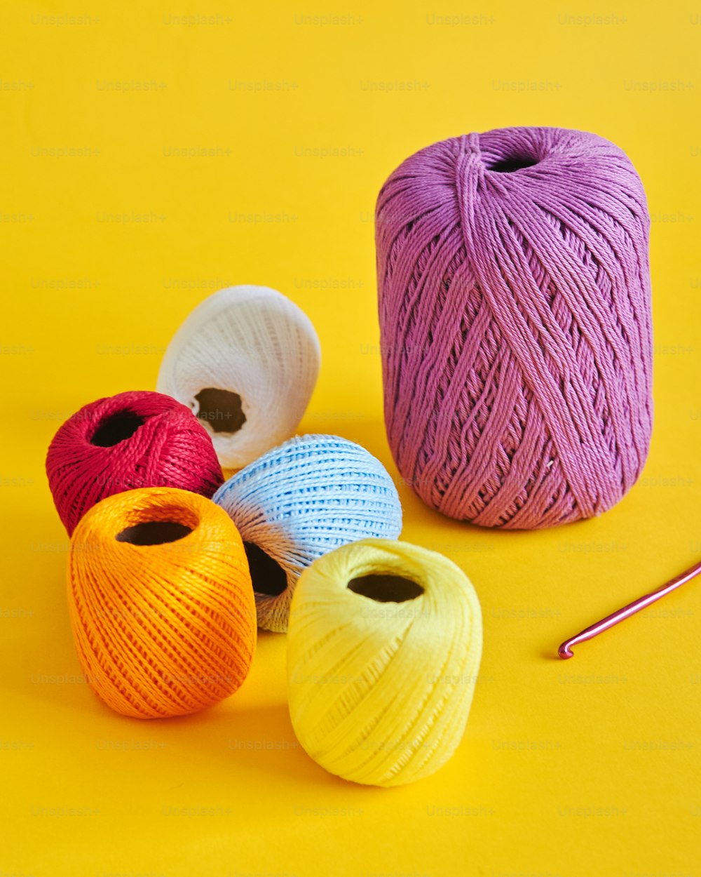 um grupo de bolas de fio ao lado de um gancho de crochê