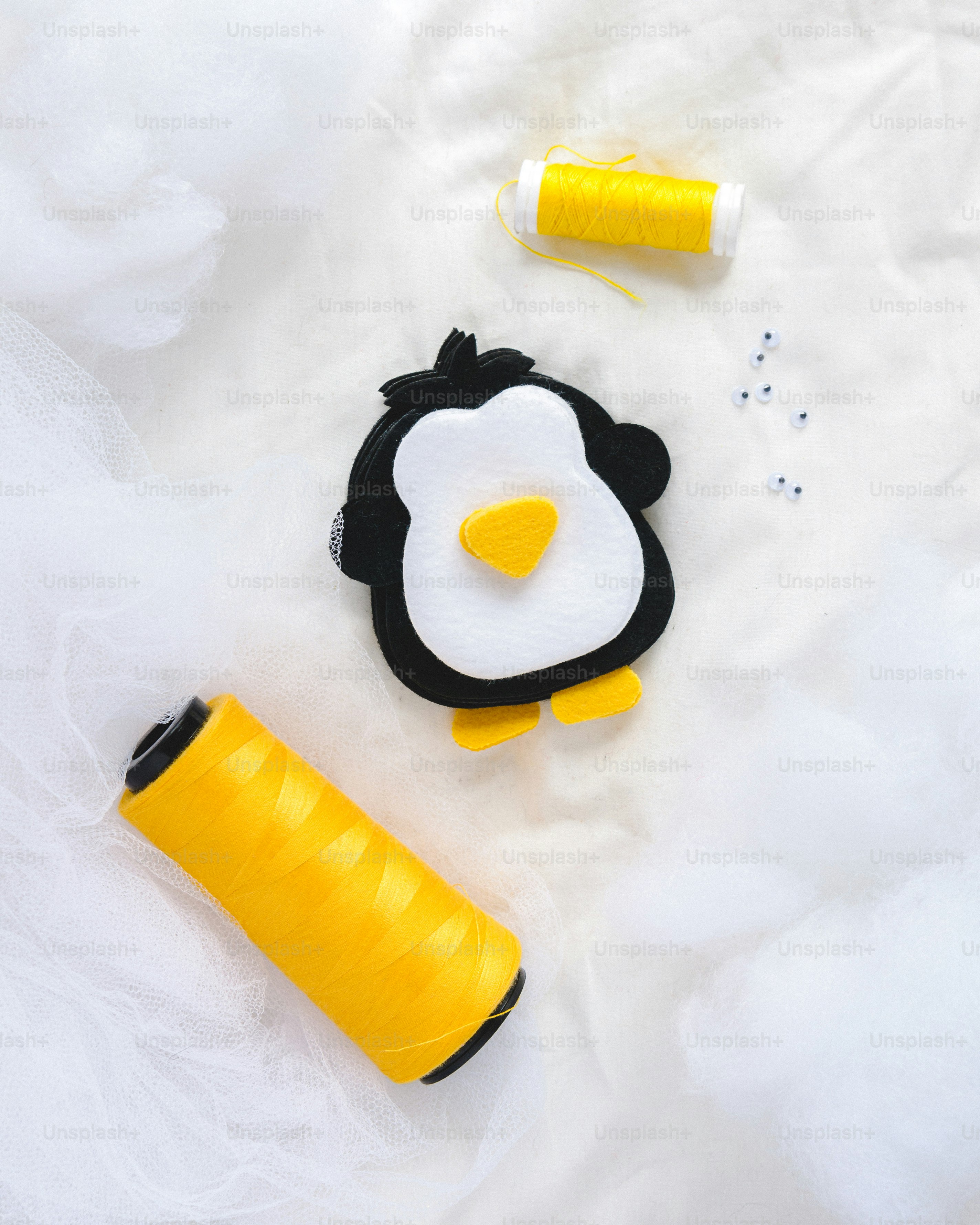 um projeto de costura com um pinguim e um carretel de linha