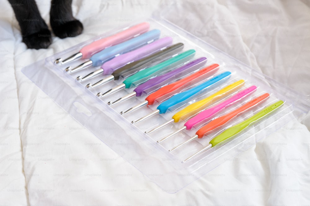 Un recipiente de plástico lleno de muchos bolígrafos de diferentes colores