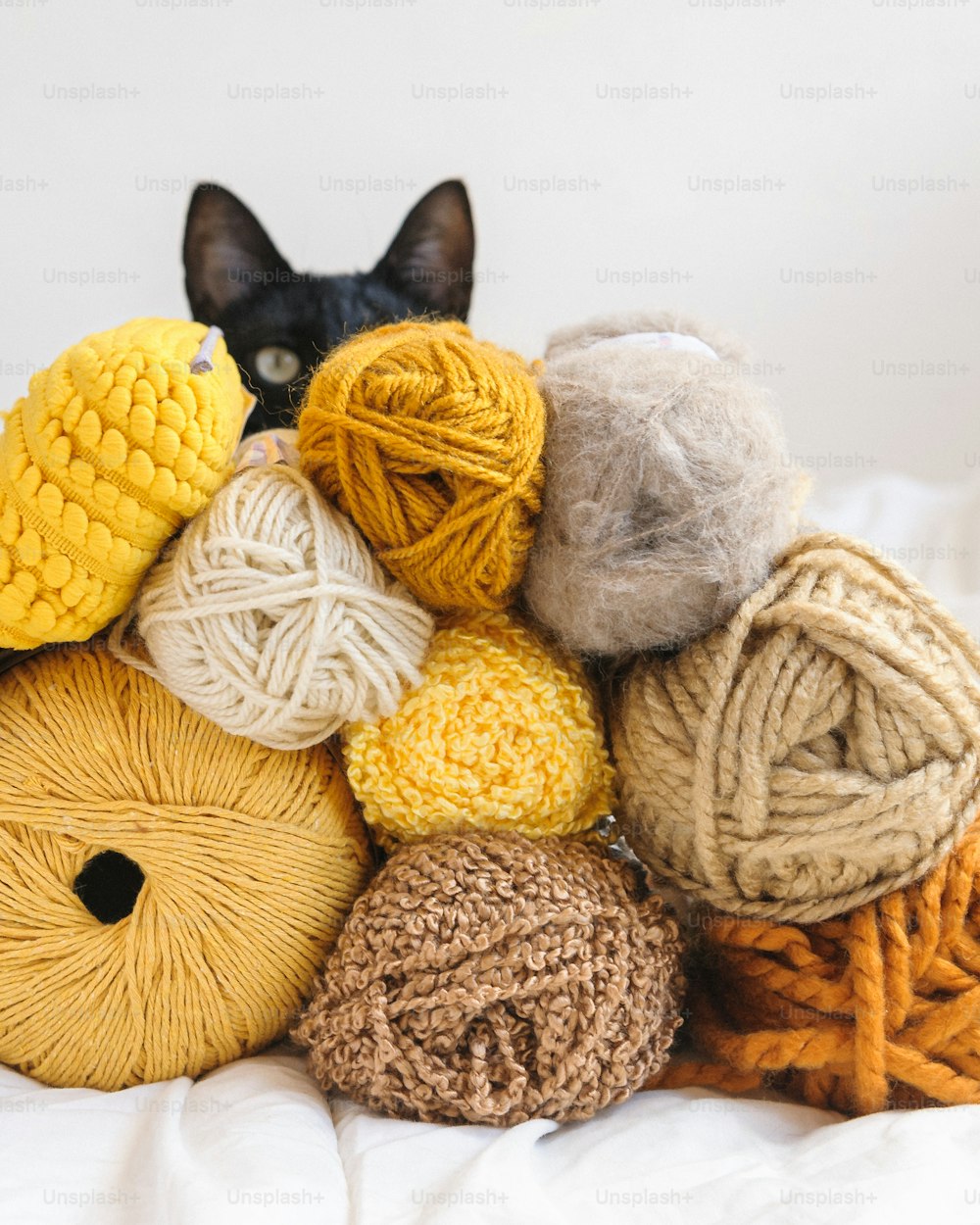 a pile of balls of yarn sitting on top of a bed