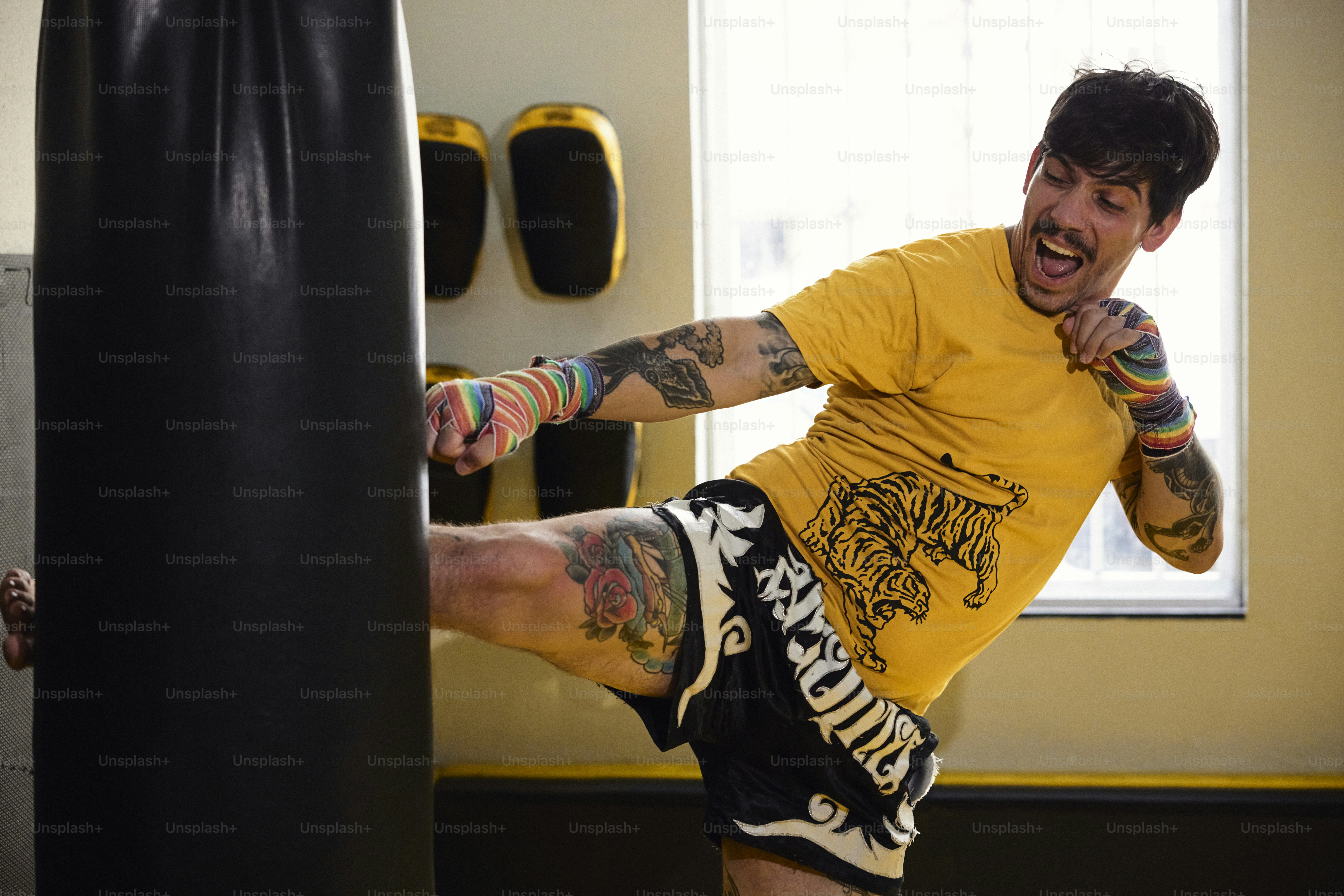 a man in a yellow shirt is kicking a punching bag